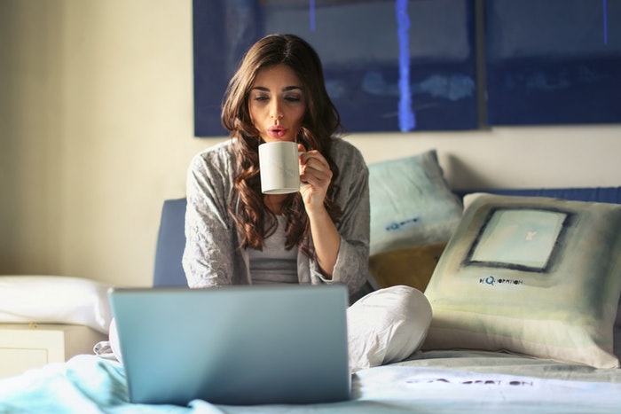 woman on bed on a computer, working remotely