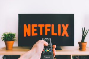 image of Netflix on tv and hand holding remote control