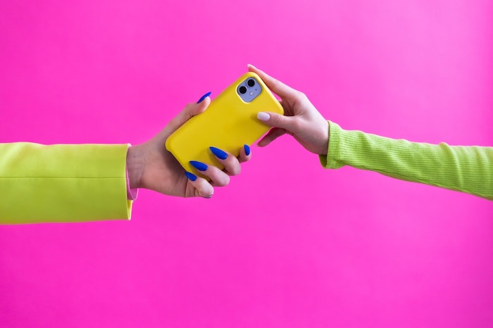 woman handing a mobile phone to another woman